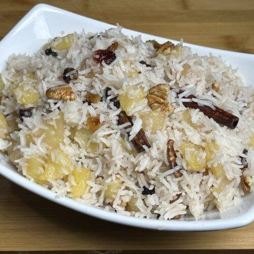 A bowl of Sweet Apple Pulao Rice garnished with apple slices and nuts