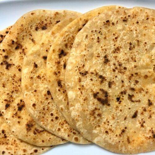 A plate of Coconut Paratha served with a side of yogurt