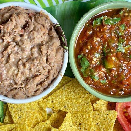 A plate of Mexican Refried Beans and Salsa served with tortilla chips and fresh vegetables