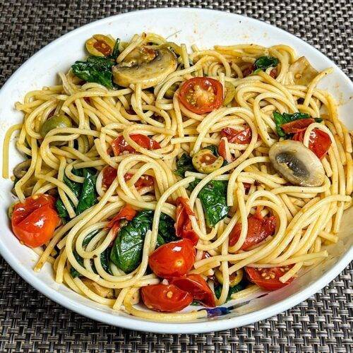 A plate of Tomato Basil Pasta garnished with fresh basil leaves