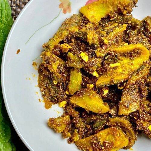 A dish of Sweet and Sour Spicy Karela garnished with sesame seeds