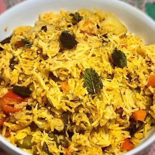 A bowl of Vegetable Biryani garnished with fresh mint leaves